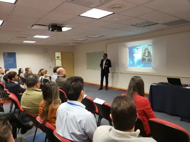 Un grupo de asistentes escuchando a un instructor mientras presenta una diapositiva en un aula para el curso Zoho CRM