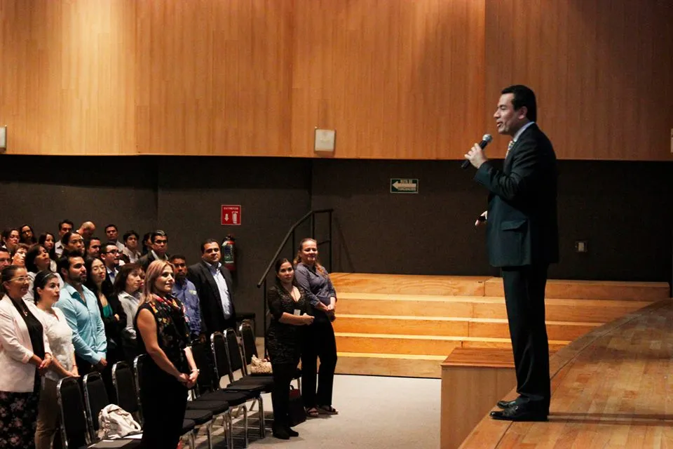 Un orador en el escenario interactúa con una audiencia atenta durante una presentación sobre el curso Zoho CRM