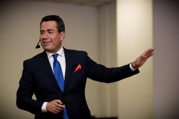 Primer plano de un orador sonriente con micrófono de diadema gesticulando mientras enseña durante el curso Zoho CRM